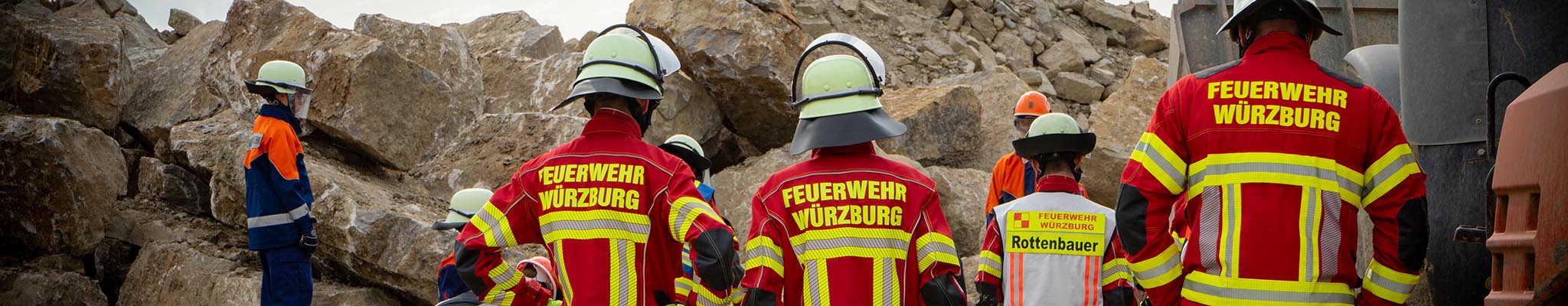 Feuerwehrleute und Jugendfeuerwehr in Einsatzkleidung bei einer simulierten Einsatzübung.